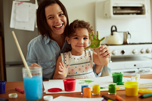 Portrait of mother and daughter painting together in kitchen