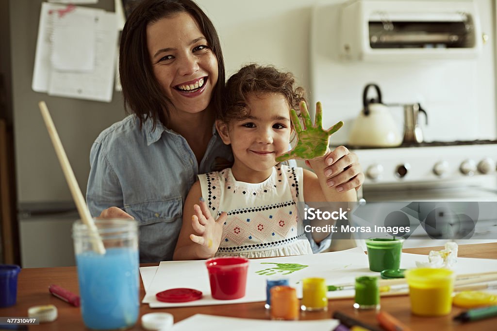 Portrait of mother and daughter painting Portrait of mother and daughter painting together in kitchen Child Stock Photo