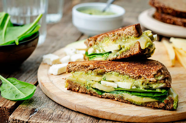 grilled rye sandwiches with cheese, spinach, pesto, avocado and goat cheese grilled rye sandwiches with cheese, spinach, pesto, avocado and goat cheese. the toning. selective focus panino stock pictures, royalty-free photos & images