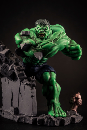 Florence, Italy - March 01, 2014: A vertical studio shot of an action figure toy of the fictional character The Incredible Hulk. Here the Hulk is standing facing the camera, against a black background and destroy a wall.