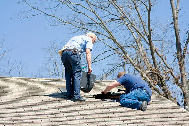 Roofing contractor repairing damaged roof on home after recent wind storms, many roofs were damaged