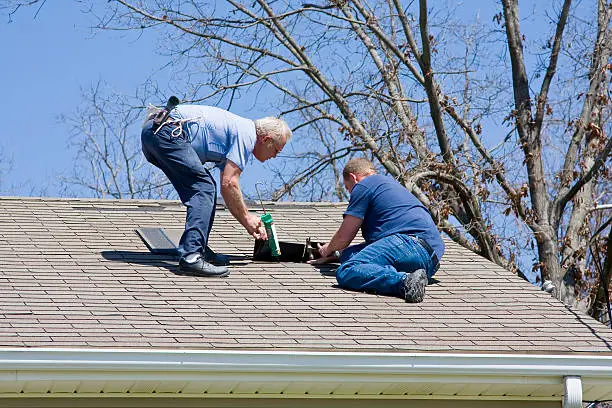Roofing contractors repairing damaged roof on home after recent wind storms, many roofs were damaged
