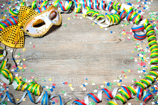 Colorful carnival background with garlands, streamer, party hats, confetti and mask
