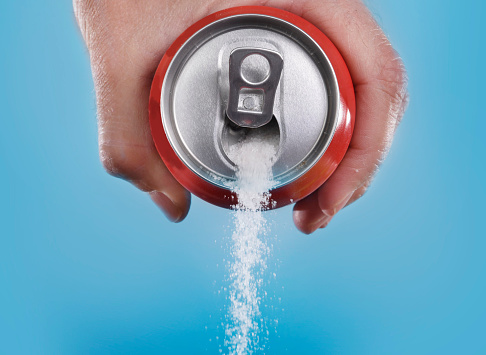 Mano agarrando soda pueden verter en metáfora de contenido de azúcar photo