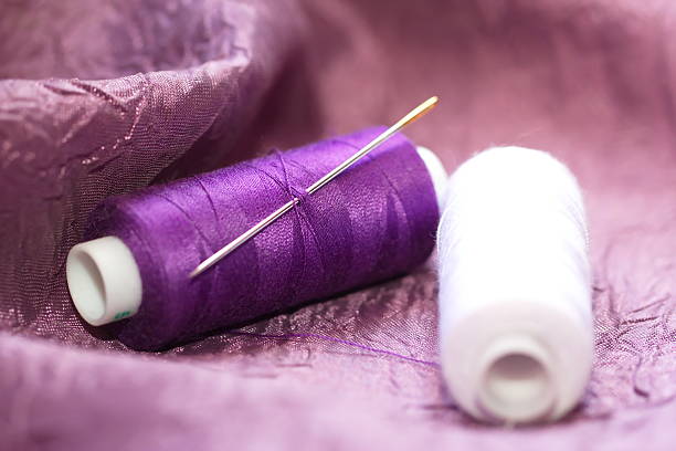 istock Needle and spools of thread on color textile 477335312