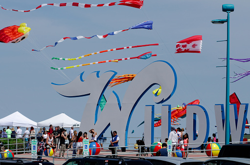 Wildwood, NJ, USA - May 24, 2015; During the annual kite festival hundreds of colorful kites are shown above the boardwalk and behind the iconic WILDWOODS sign, positioned of Rio Grande Ave in Wildwoods, NJ. With a backdrop of near blue skies hundreds of kite-enthusiasts, onlookers and beach-goers enjoy a beautiful Memorial Day Weekend down the Shore.  The annual Wildwoods International Kite Festival is said to be the largest of its kind in the U.S. (photo by Bastiaan Slabbers)