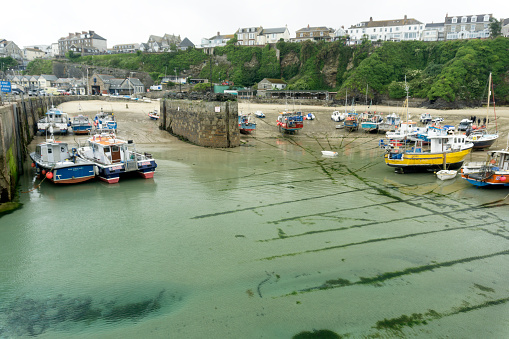 Newquay, UK - June 13, 2015: Newquay Harbour at low tide on a bright but overcast June day.  Various boats anchored in the Harbour.