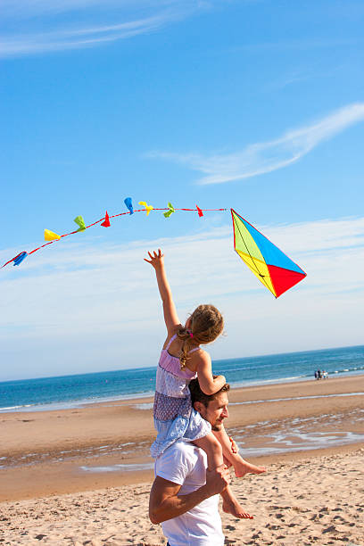 vater und tochter mit kite am strand - father directly below child looking up stock-fotos und bilder