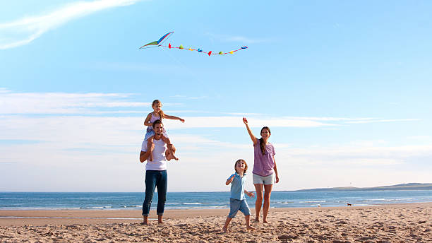 familie am strand mit kite - father directly below child looking up stock-fotos und bilder