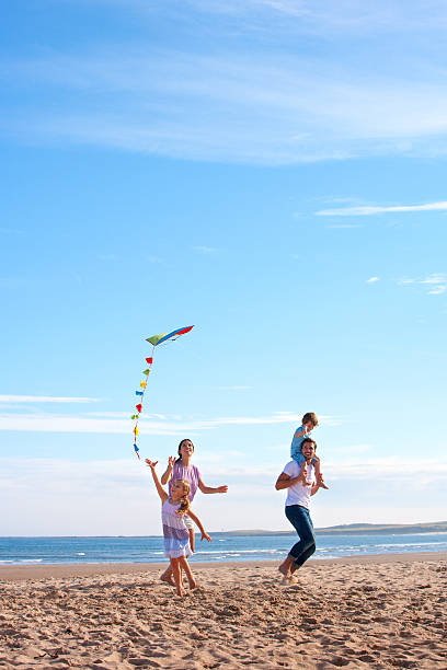 familie am strand mit kite - father directly below child looking up stock-fotos und bilder