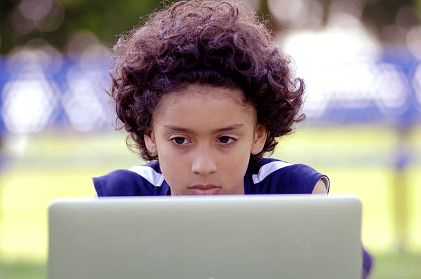 African American boy using a laptop computer outside stock photo