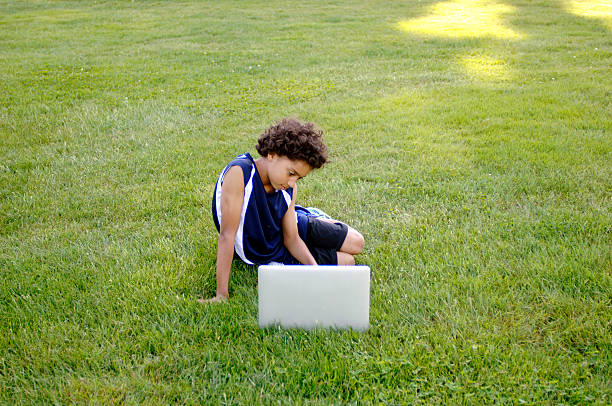African American boy working on a laptop computer outside. stock photo