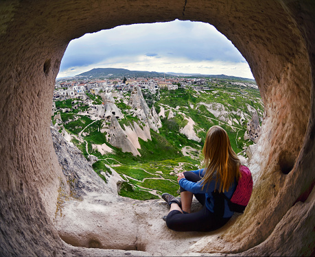 Woman looking into the distance against the background of incredible landscape with  mountains , geological structures in Goreme, Cappadocia,  Turkey