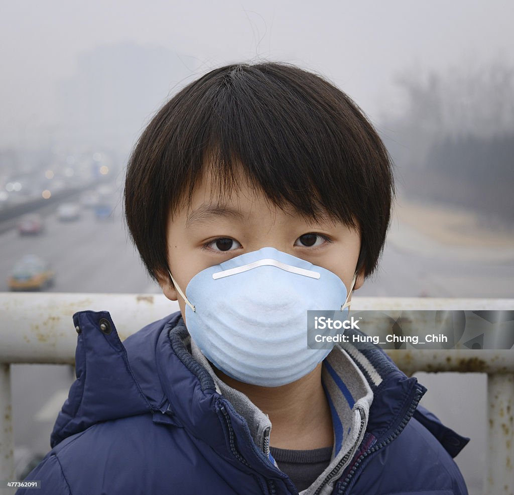 Asian boy wearing mouth mask against air pollution (Beijing) Asian child protects himself against air pollution by wearing mouth mask Asia Stock Photo