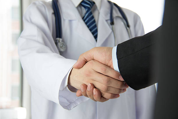 Doctor and businessman shaking hands stock photo