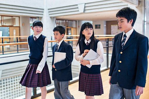 Japanese students walking in the school corridors, two boys and two girls together talking.