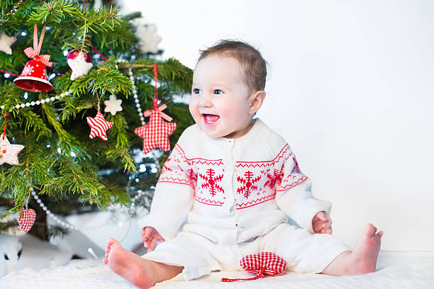 istock Funny laughing baby girl playing under decorated Christmas tree 477372385
