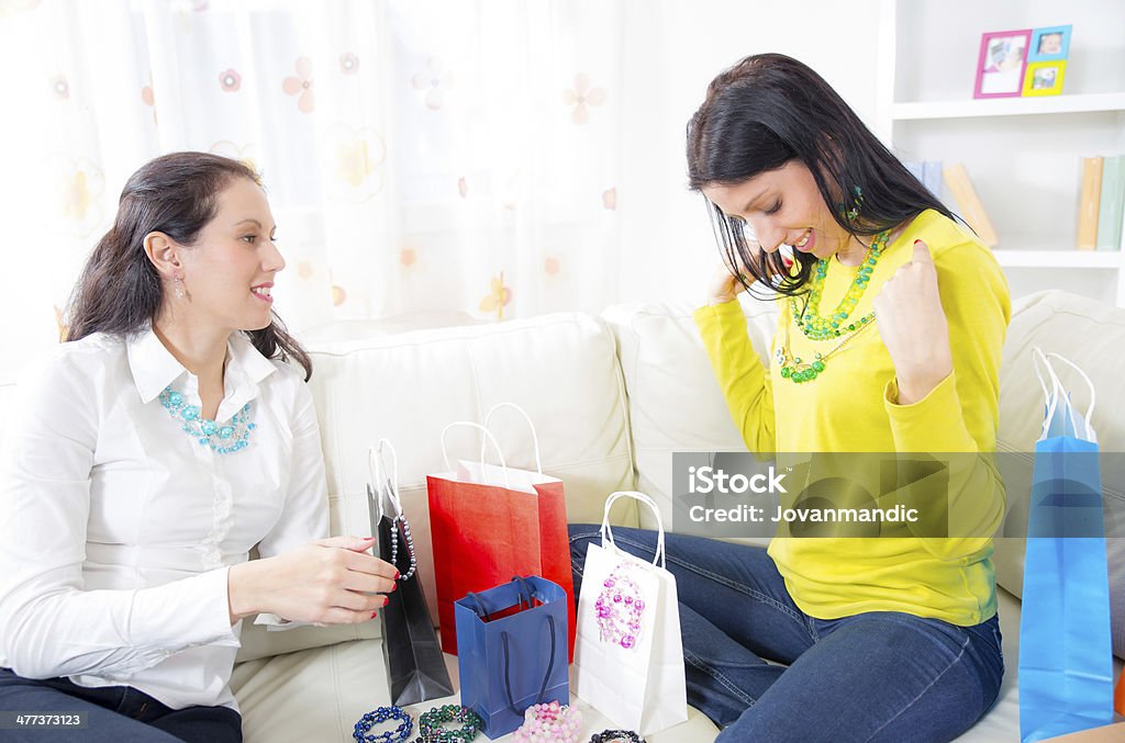 Młodych kobiet siedzi na kanapie z torby na zakupy i biżuteria - Zbiór zdjęć royalty-free (Biżuteria)