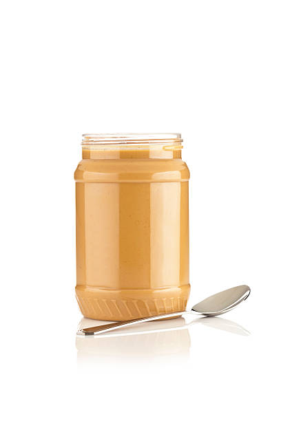 An empty peanut butter jar with spoon inside; isolated on white.