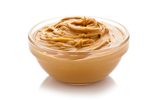 Bowl of peanut butter isolated on white background
