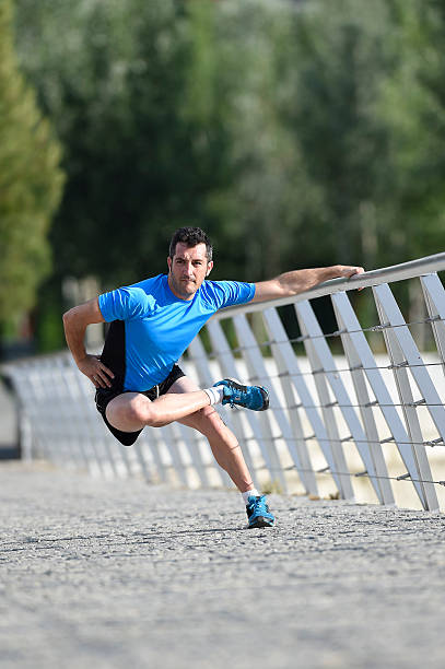 istock man stretching legs warming up muscles before running in city 477378324