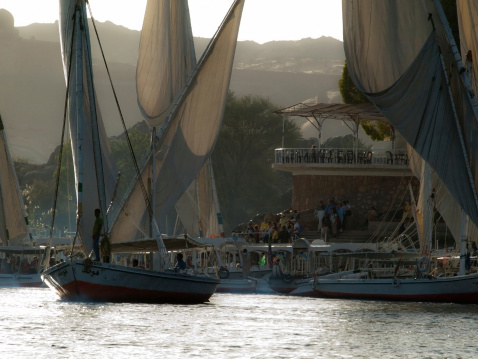 Aswan, Egypt - December 23, 2010: People on the Felucca boats down the Nile River at Aswan in Egypt. A cruise on a Felucca is a popular activity for tourists visiting Aswan.