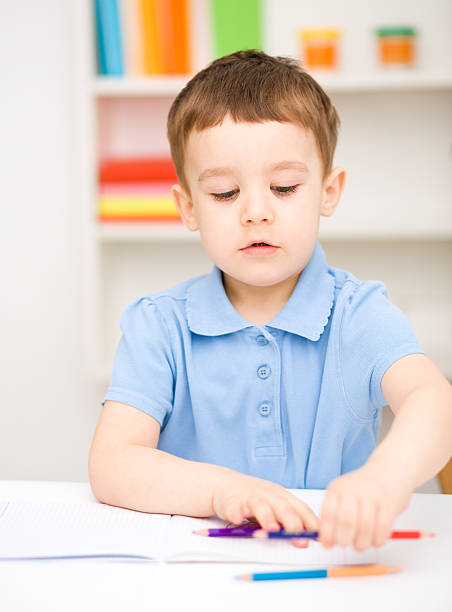 istock Little boy is drawing on white paper 477379885