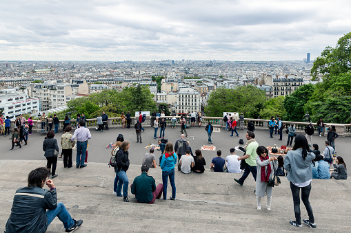 Paris, France - May 28, 2015: Tourists admiring the skyline of Paris from the stairs of the Sacre Coeur Basilica, the highest city point of Paris
