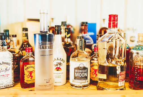 Black Forest, Colorado, USA - May 30, 2015: A horizontal shot of a large collection of assorted bottles of alcohol. Visible in this image are Jack Daniels Winter Jack, Fireball Cinnamon Whisky, which is made by the Sazerac Company, American Harvest Organic Spirit, Malibu, Midnight Moon and more.