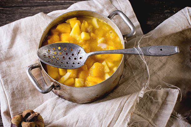 Exotic fruit jam Making mango chutney or jam in vintage aluminum pan over old wooden table with whole and slice mangosteen. Dark rustic atmosphere kaki marmelade stock pictures, royalty-free photos & images