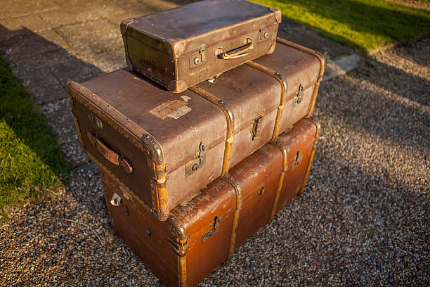 A stack of old fashioned antique trunks and cases in evening sunlight representing old time travel and adventure and resembling the wartime period in 20th century Europe.