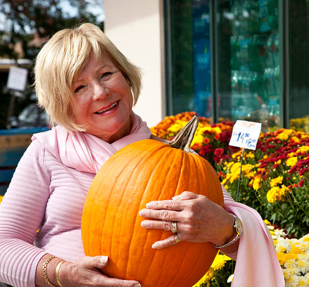 年配の女性のショッピング街、通電大きなカボチャ - single flower flower autumn pumpkin ストックフォトと画像