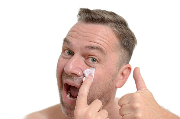 istock Man applying moisturizer to his skin 477390546