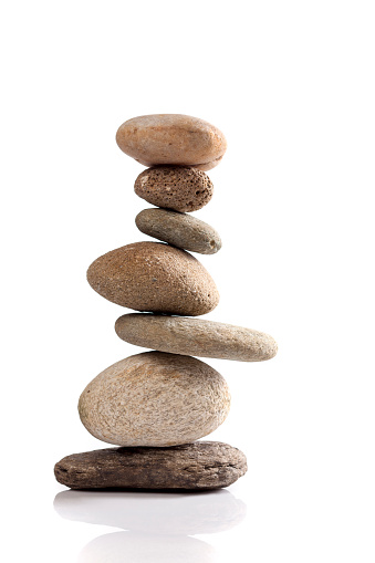 Balanced stack of different river stones on white background