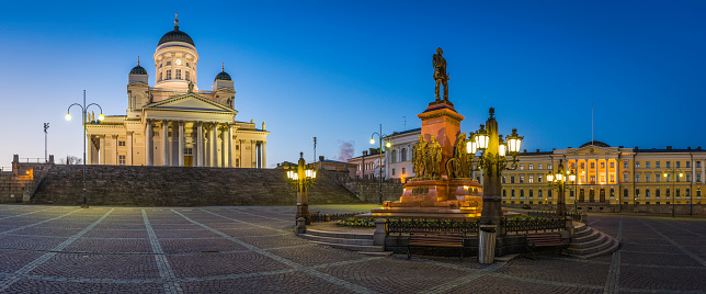 The iconic domes and portico of Helsinki Cathedral illuminated at dusk overlooking the historic statue of Alexander II, Senate Square and the Government Palace, home of the Prime Minister's office, in the heart of Finland's picturesque capital city. ProPhoto RGB profile for maximum color fidelity and gamut.