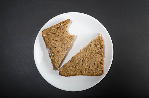 Delicious whole wheat sandwich on white plate and black background. 