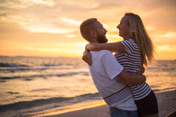 istock Cheering couple being affectionate on beach at sunset 477392586