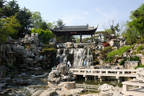 Yangzhou, China - April 21, 2015. Tourists enjoy their time at waterfalls in a scenic public park in Yangzhou. Yangzhou is an ancient city located in the south of Jiangsu Province, China, with a history of over 2,000 years.