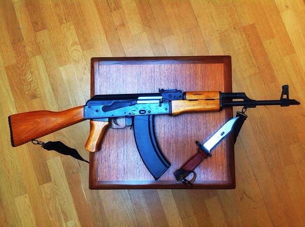 Ak-47 and bayonet birds eye view A Kalashnikov rifle and Russian bayonet on a vintage 60s G Plan table , wood background. Anti-Terrorism Day stock pictures, royalty-free photos & images