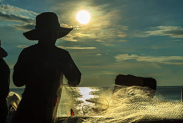 Ominous fishermen with nets in the morning. Binh Thuan sea, Vietnam - June 4th, 2014: A man fishing on a grid carving the early morning when the sun was up in the sea of Binh Thuan, Vietnam basket boat stock pictures, royalty-free photos & images