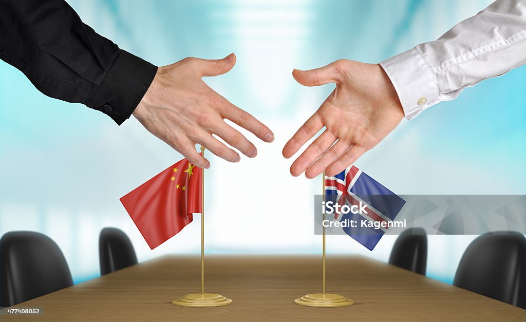 China and Iceland diplomats agreeing on a deal Two diplomats from China and Iceland extending their hands for a handshake on an agreement between the countries. 2015 Stock Photo