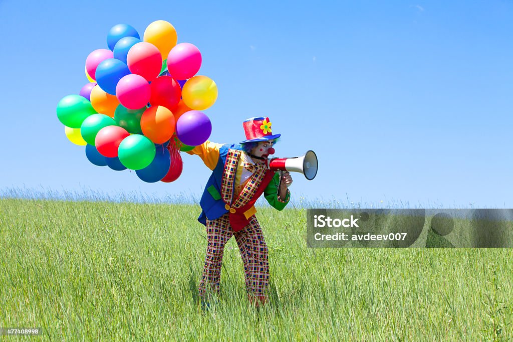 Clown holding balloons and crying  to megaphone Clown holding balloons and crying  to megaphone. Outdoors. 2015 Stock Photo
