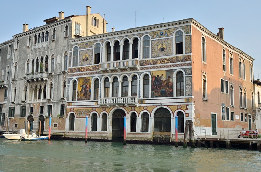 Venice, Italy - August 11, 2014: Some people sitting on a bench next to Palace Barbarigo at the Gran Canal in  Venice, northern Italy.