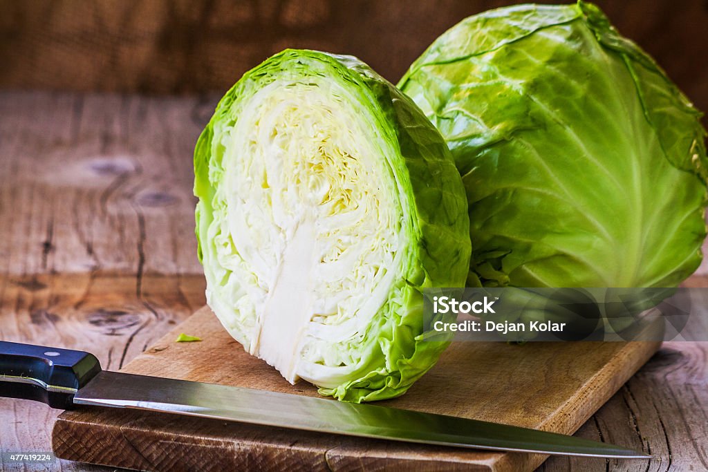 Fresh cabbage cross section with water drops Fresh green cabbage cross section with water drops on rustic wooden cutting board, kitchen knife in forground. Close up, selective focus Cabbage Stock Photo