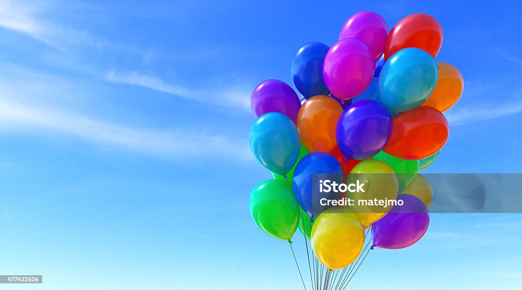 Balloons B08 A group of colorful balloons tied together into a bunch, isolated on a soft blue sky background. The balloons surface looks slightly marbled and they come in all colors of the rainbow. Balloon Stock Photo