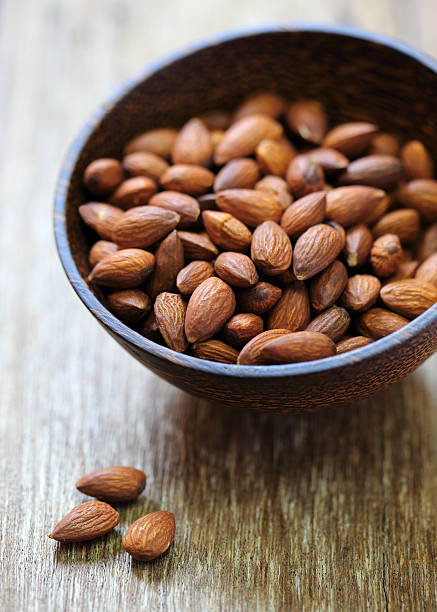 istock Almonds in brown bowl on wooden background 477422608