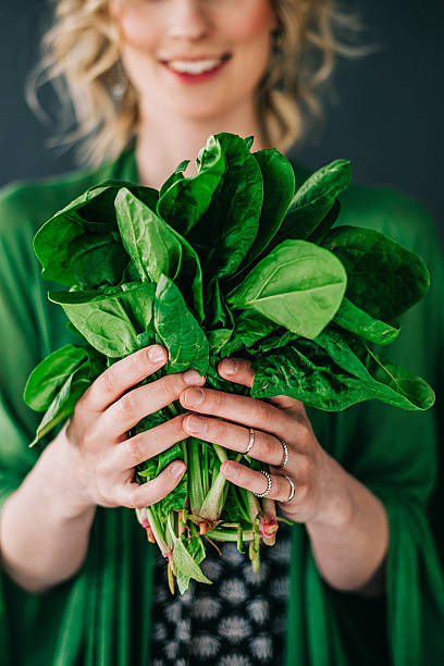 joven mujer sosteniendo espinaca leafs ensalada - vegetal con hoja fotografías e imágenes de stock