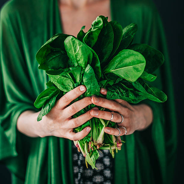 istock Young woman holding spinach leafs salad 477423374
