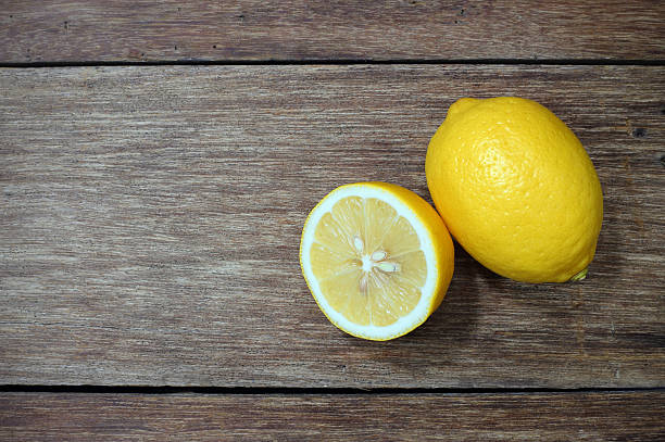 istock Freshly cut half and whole lemons on wood background 477423874
