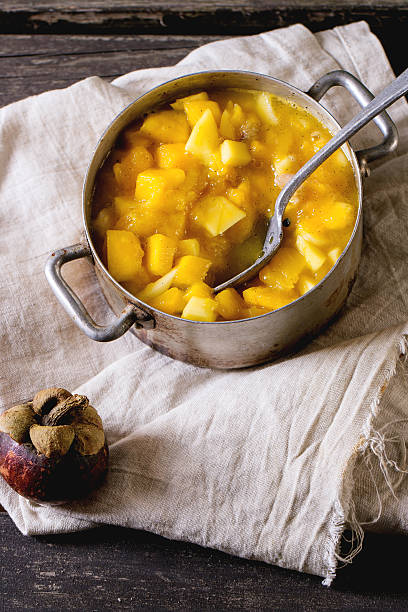 Exotic fruit jam Making mango chutney or jam in vintage aluminum pan over old wooden table with whole and slice mangosteen. Dark rustic atmosphere kaki marmelade stock pictures, royalty-free photos & images
